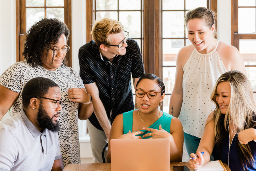 Group of people talking around a laptop